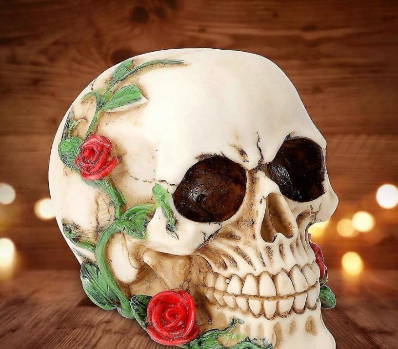 Resin skull figurine with red roses and green vines