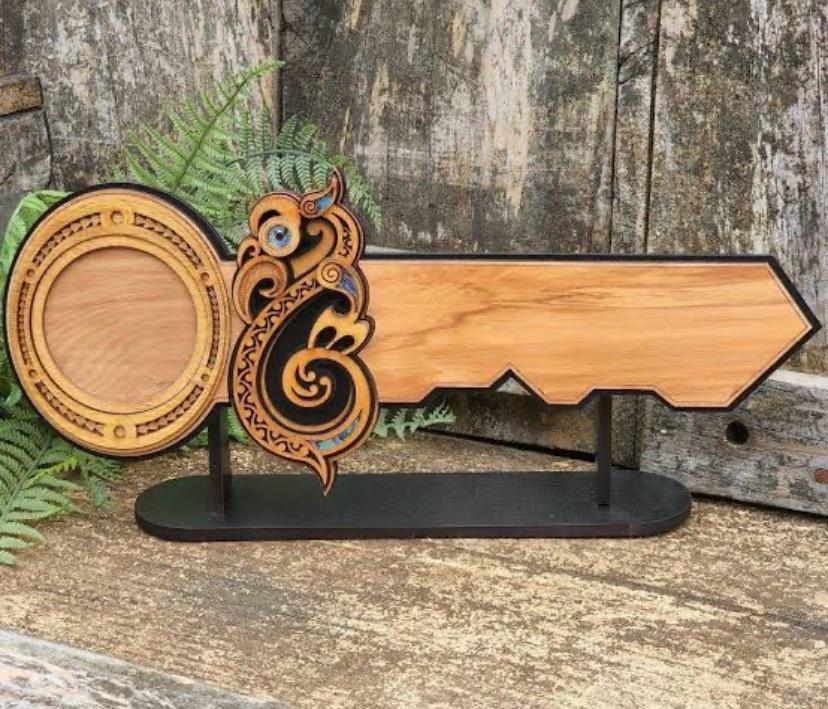 Māori-inspired decorative wooden 21st birthday key on black display stand