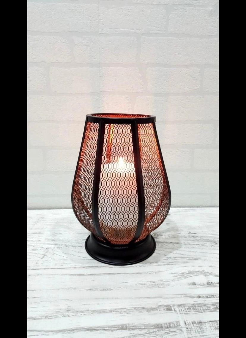 Black wire mesh tulip lantern candle holder glowing with warm amber candlelight